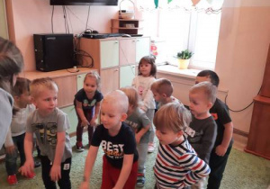 Dzieci stoją w sali i tańczą do muzyki